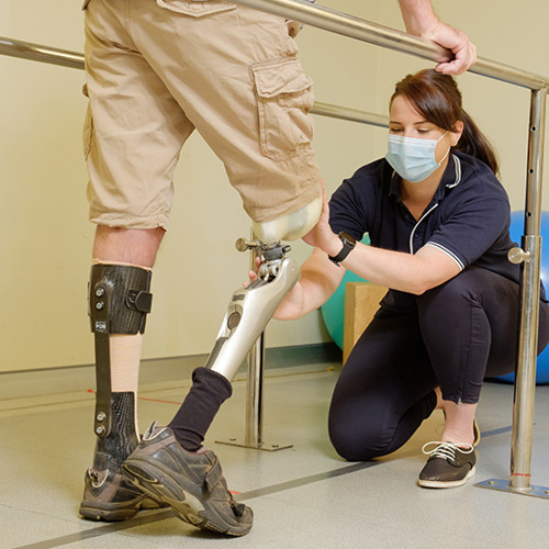Prosthetics & Orthotics A medical professional assisting a man with the movement of his prosthetic leg