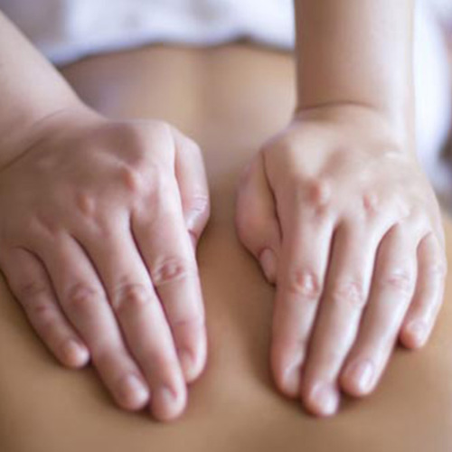 Oncology Massage Close up image of two hands that are cupped and placed on the back of person receiving massage