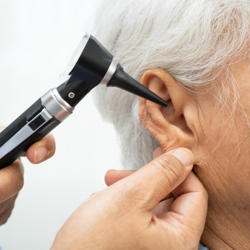 Healthcare professional examining a patient's ear with an otoscope during a hearing or ear health assessment.