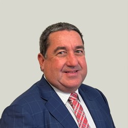 A person is wearing a blue checkered suit jacket, a white dress shirt with small patterns, and a red and white striped tie. The background is plain light gray.