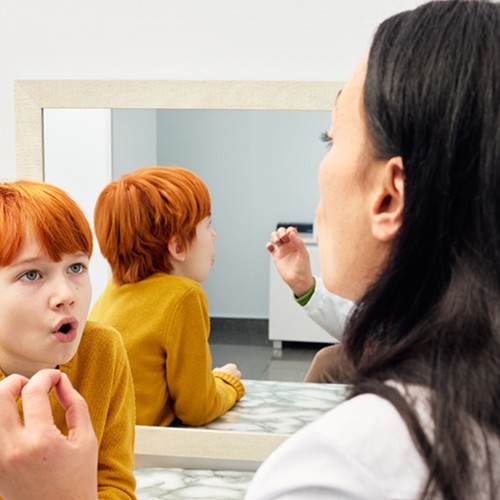 Speech Pathologist practicing enunciation with a small boy