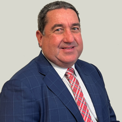 A person is wearing a blue checkered suit jacket, a white dress shirt with small patterns, and a red and white striped tie. The background is plain light gray.